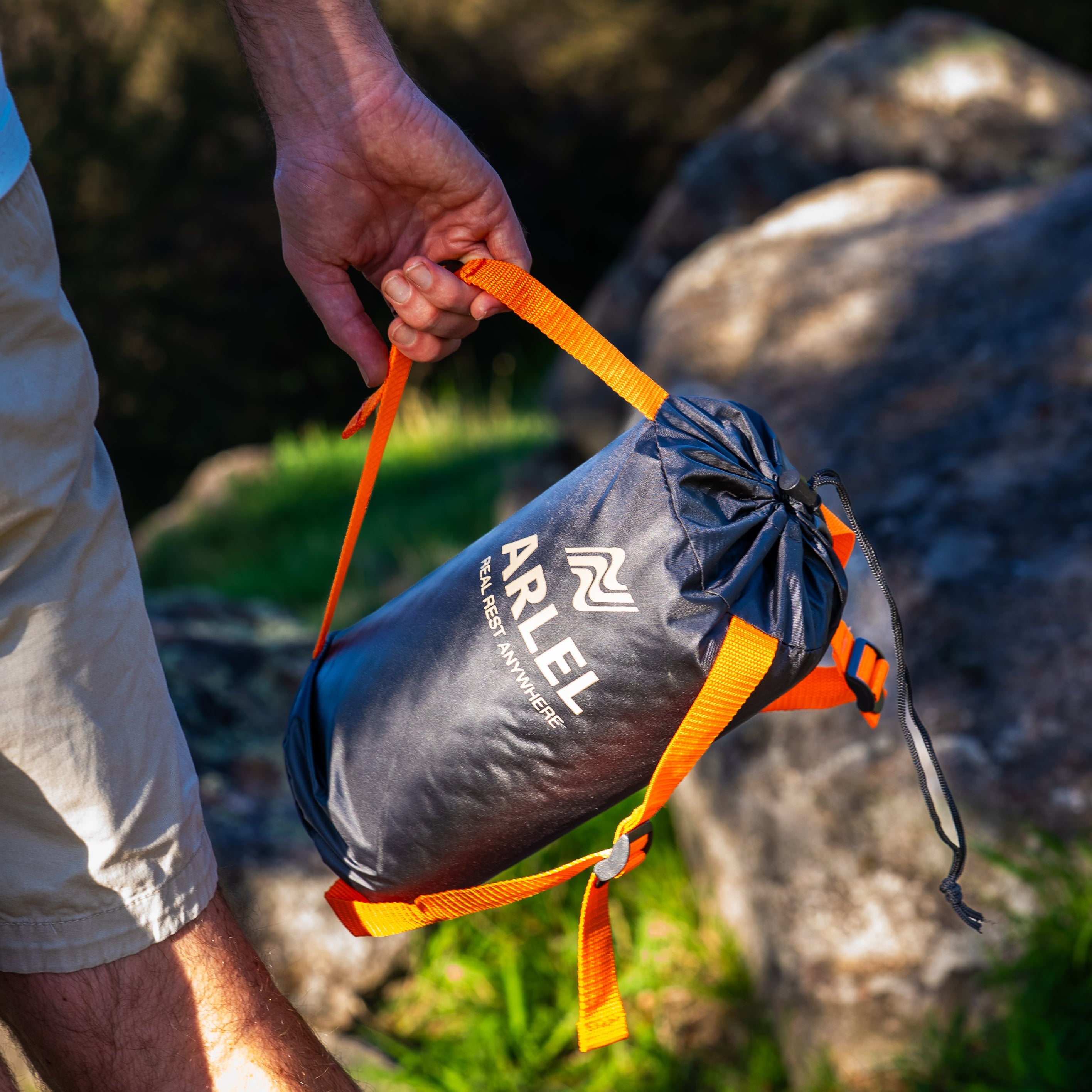 Person holding a black ARLEL Pillow carry bag in an outdoor setting